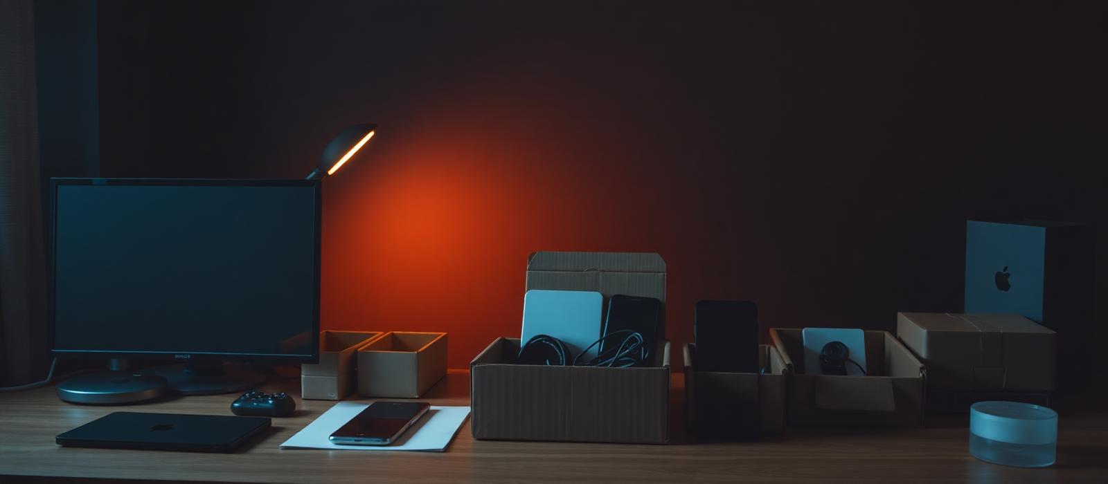 Small tech gadgets from Temu in shipping boxes on a dark desk